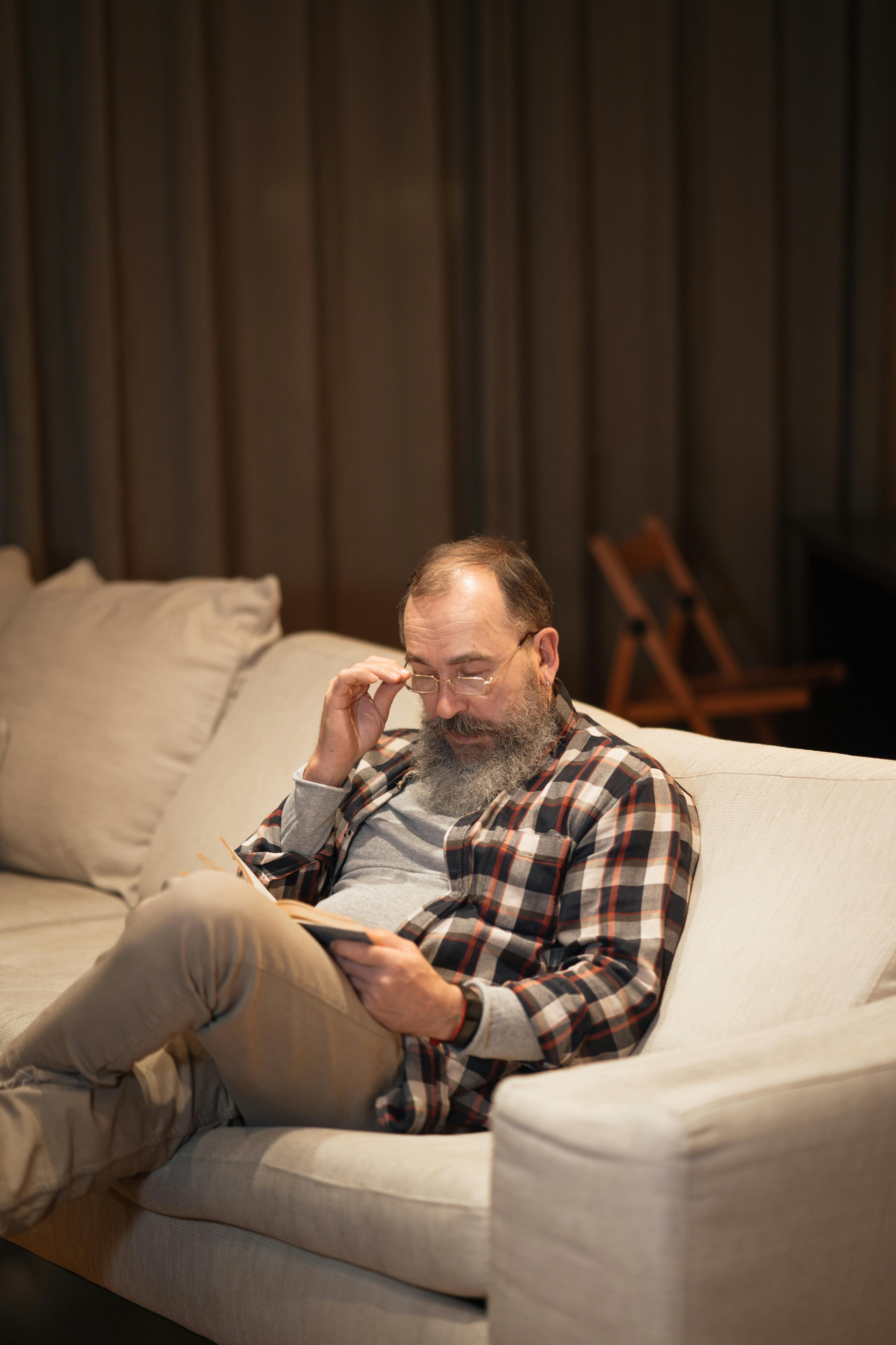 Senior man reading peacefully on couch, representing the benefits of annuities for stress-free retirement income.