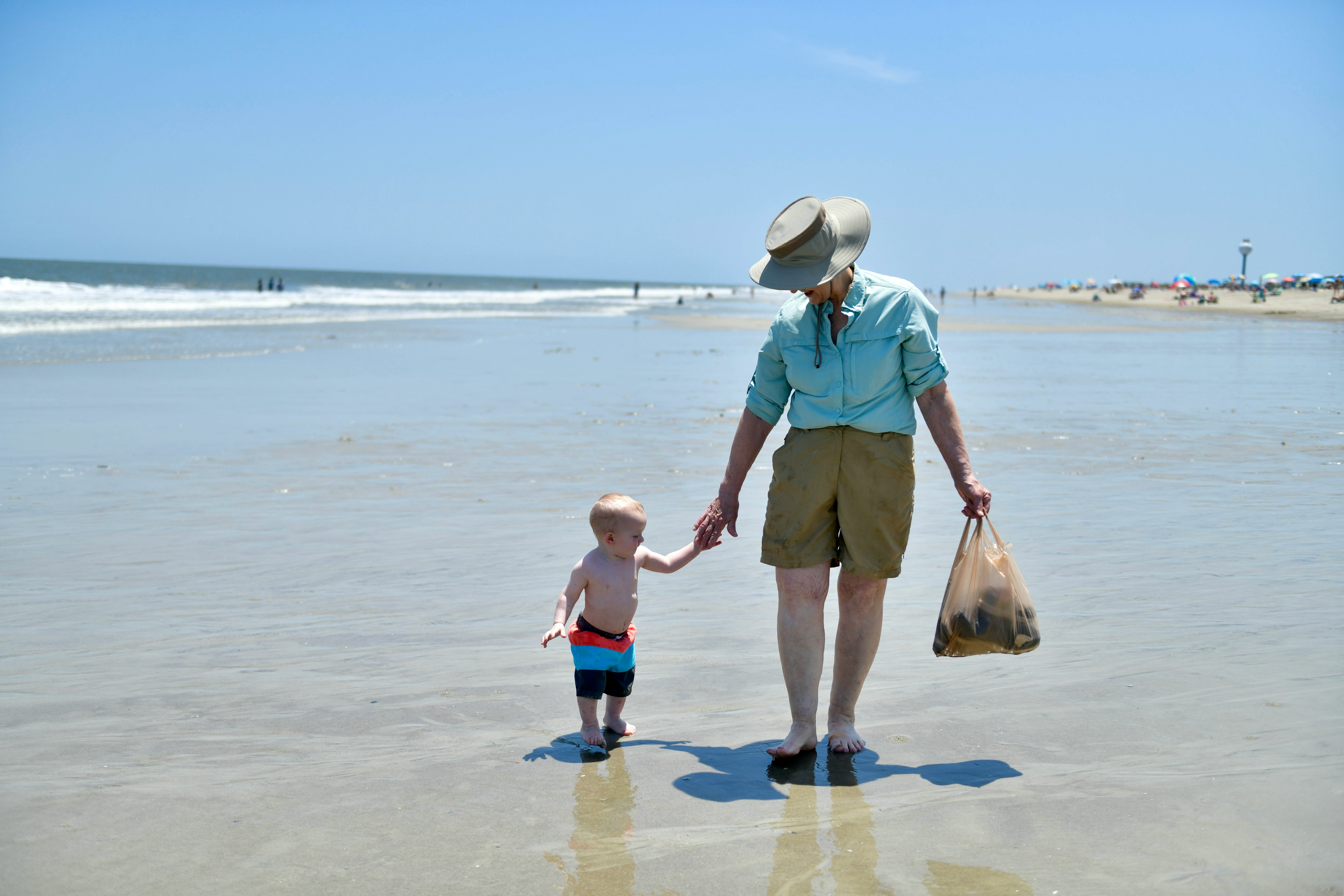 Grandfather walking on beach with grandson, illustrating how annuities support a stable and joyful retirement lifestyle.