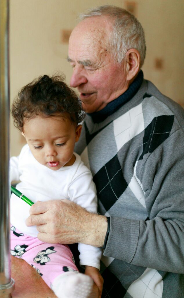 Grandfather holding baby while reviewing paperwork, symbolizing secure retirement income and annuity planning